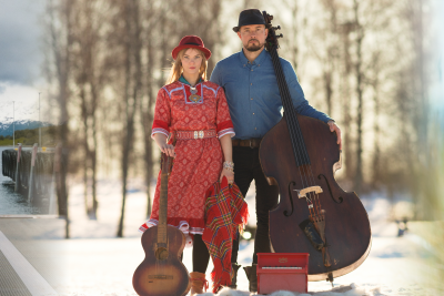 Header image. A composite image of three different images, the film poster for Hvor er ferga mi, A picture of the Band Arvvas posing with their instruments in a snowy forest, and Elina Ijäs posing in a field, covered in a blanket